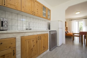 Enjoy a well-equipped kitchen with a dishwasher and stainless steel refrigerator, adjacent to a dining area with a wooden table and chairs.