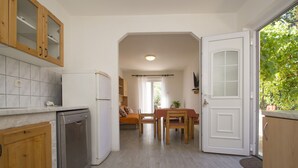 A kitchen with wooden cabinets, a dishwasher, and a dining area with a table and chairs. - Seafront Apartment Dana (Vela Luka)