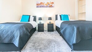 Hotellihuoneessa on kaksi sänkyä, joissa kummassakin on harmaa kalanruotokuvioinen peitto ja sininen tyyny. Sängyn vieressä on yöpöydät, joissa on lamput ja pieni laatikko. Seinällä, sänkyjen yläpuolella, on taulu, jossa on kuvattuna kukkia.
