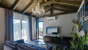 Een moderne woonkamer met een grote bank, een televisie en een kroonluchter.