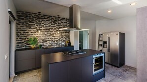 Een moderne keuken met een backsplash van natuursteen, roestvrijstalen apparatuur en hanglampen.