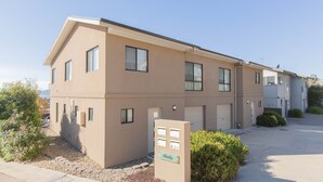 Un immeuble d’appartements à deux étages, avec une façade de couleur beige, de nombreuses fenêtres et une petite allée.