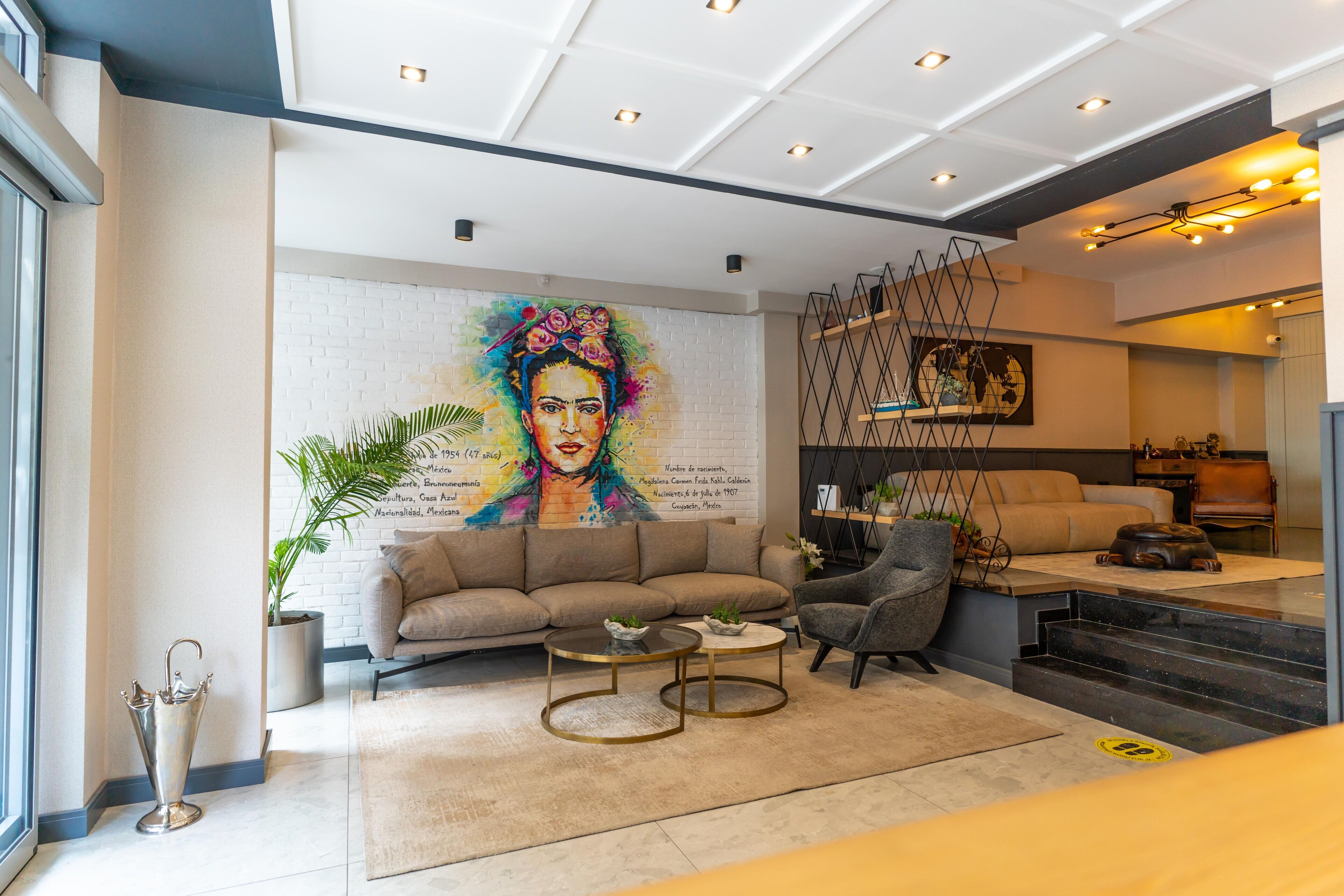 Un salon moderne avec un canapé, des tables basses et une fresque murale.