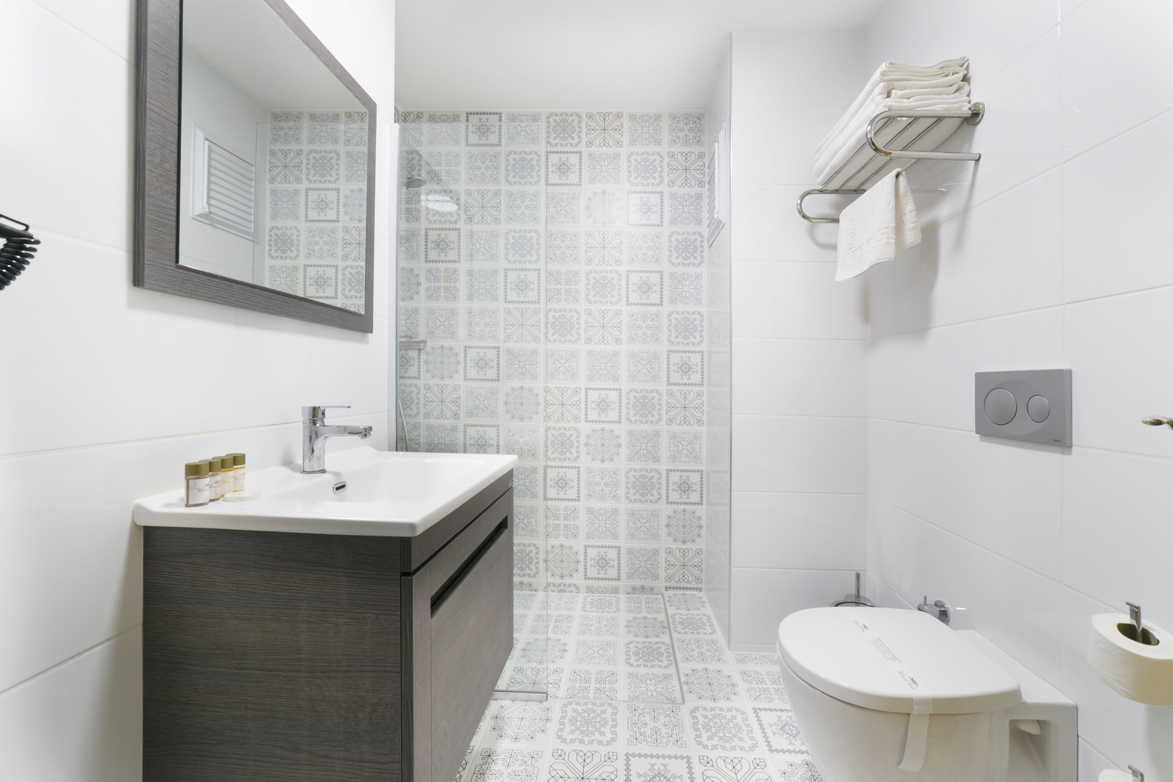 Une salle de bain moderne équipée d’un lavabo, d’un miroir, de toilettes et d’un porte-serviettes.