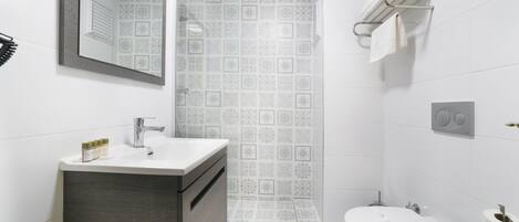 A modern bathroom with a sink, mirror, toilet, and towel rack.