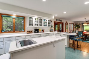 Una cocina moderna con armarios blancos, una isla central y un comedor con un letrero que dice 'WELCOME'.