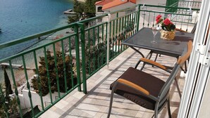 Varanda com mesa e cadeiras, vista para a praia e o mar.