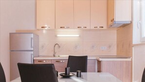 Uma cozinha moderna com frigorífico duplo, pia e área de jantar com mesa de vidro e cadeiras pretas.