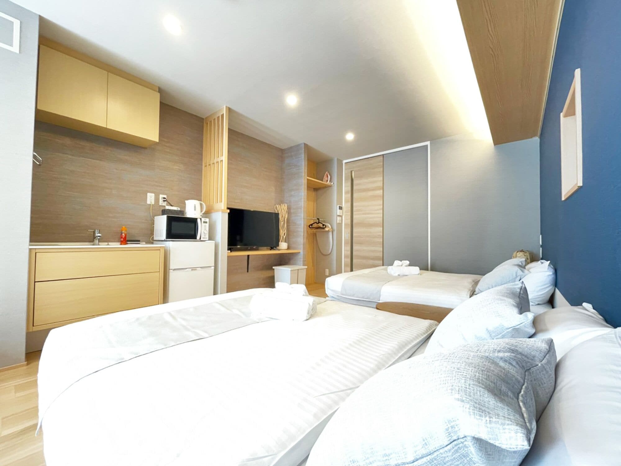 Een moderne hotelkamer met twee bedden, een kitchenette en een inloopkast.