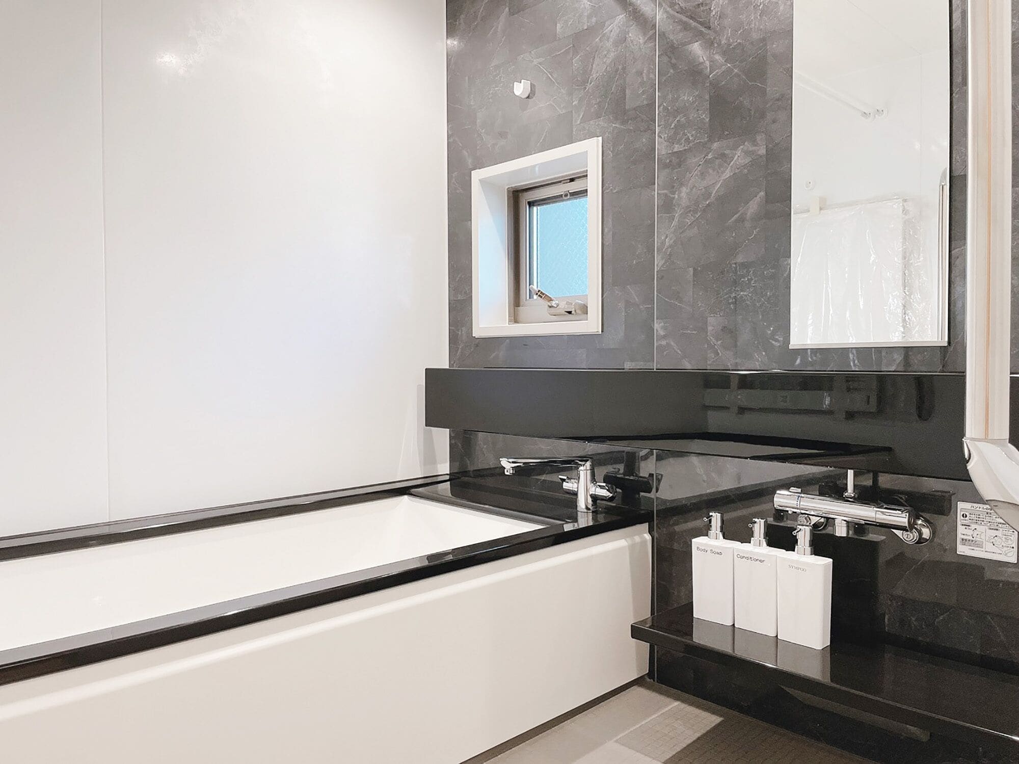 Ein modernes Badezimmer mit einer großen Badewanne, einem Spiegel und einer schwarzen Ablagefläche.