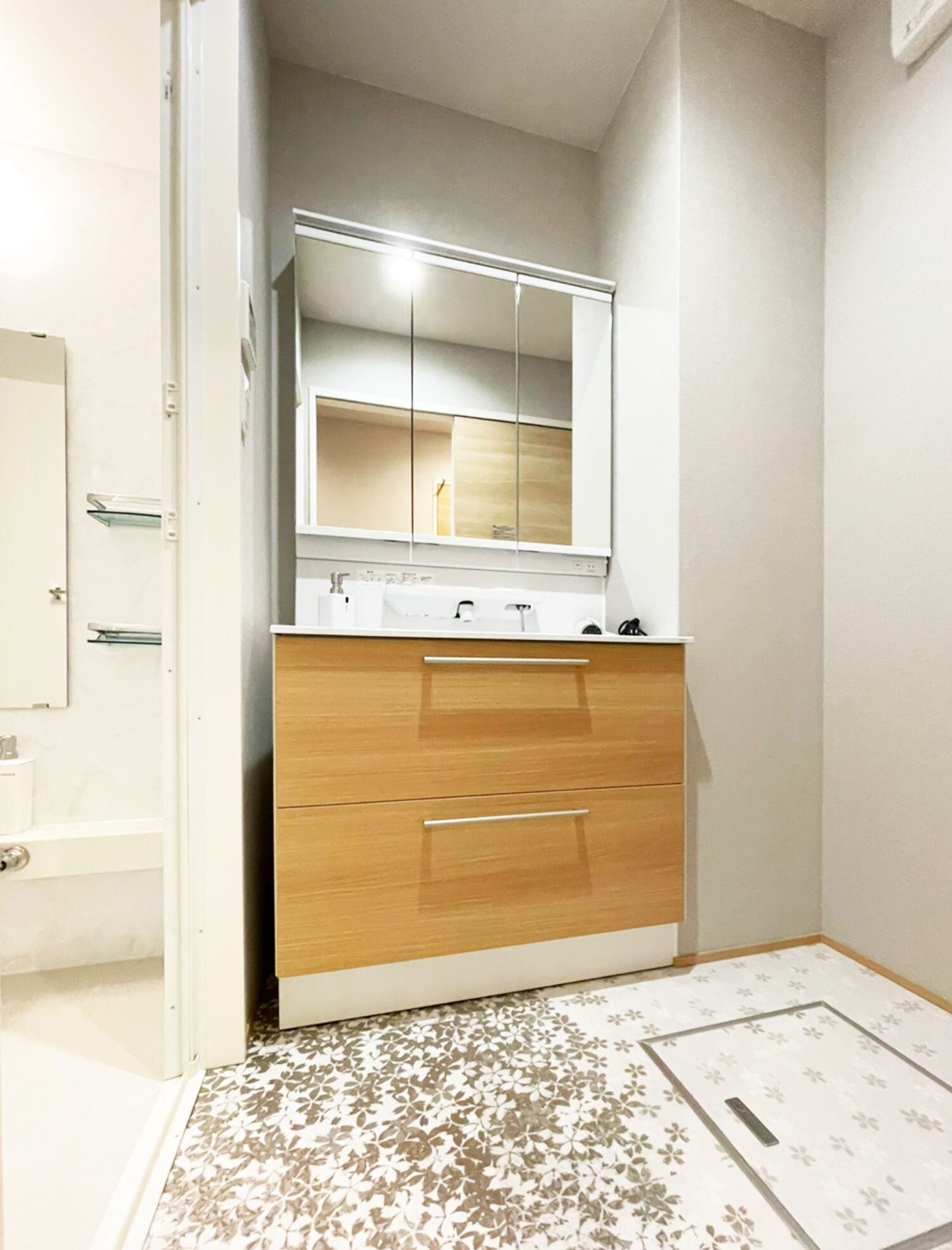 A bathroom with a wooden vanity, a mirror, and a patterned floor.