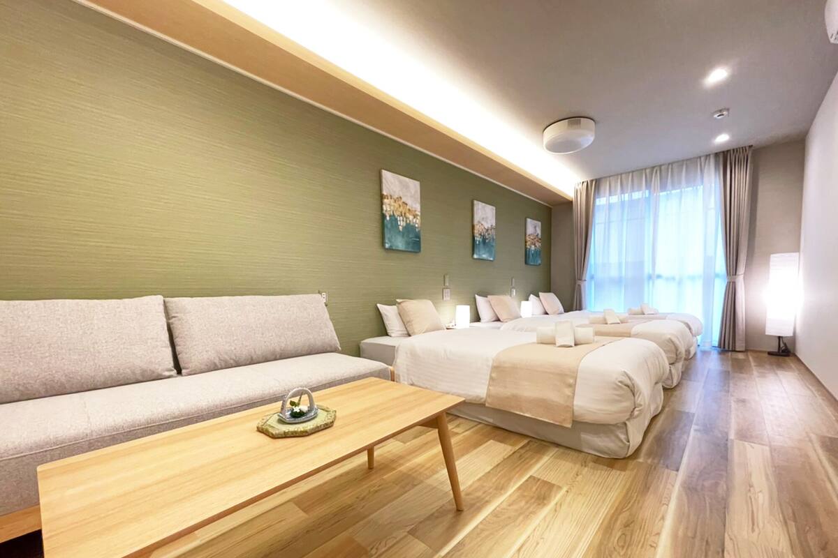 Una habitación de hotel con un sofá, una mesa de madera y varias camas.