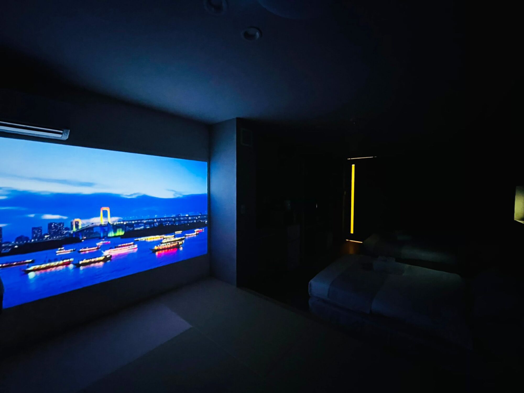 Una sala de estar moderna con un televisor de pantalla plana grande mostrando un paisaje urbano al atardecer.