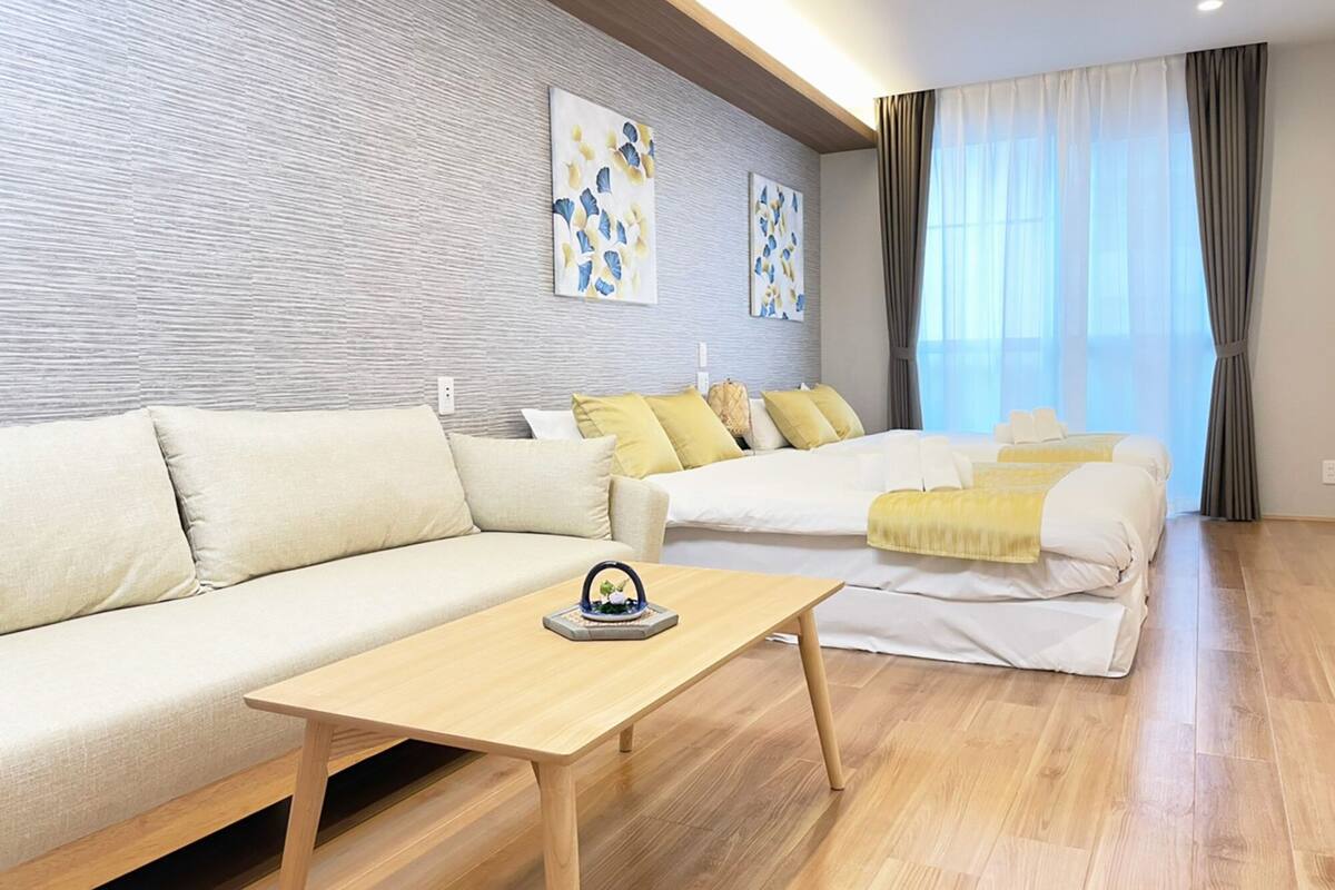 Una habitación de hotel moderna con sofá, cama, una mesa de centro de madera y obras de arte en las paredes.