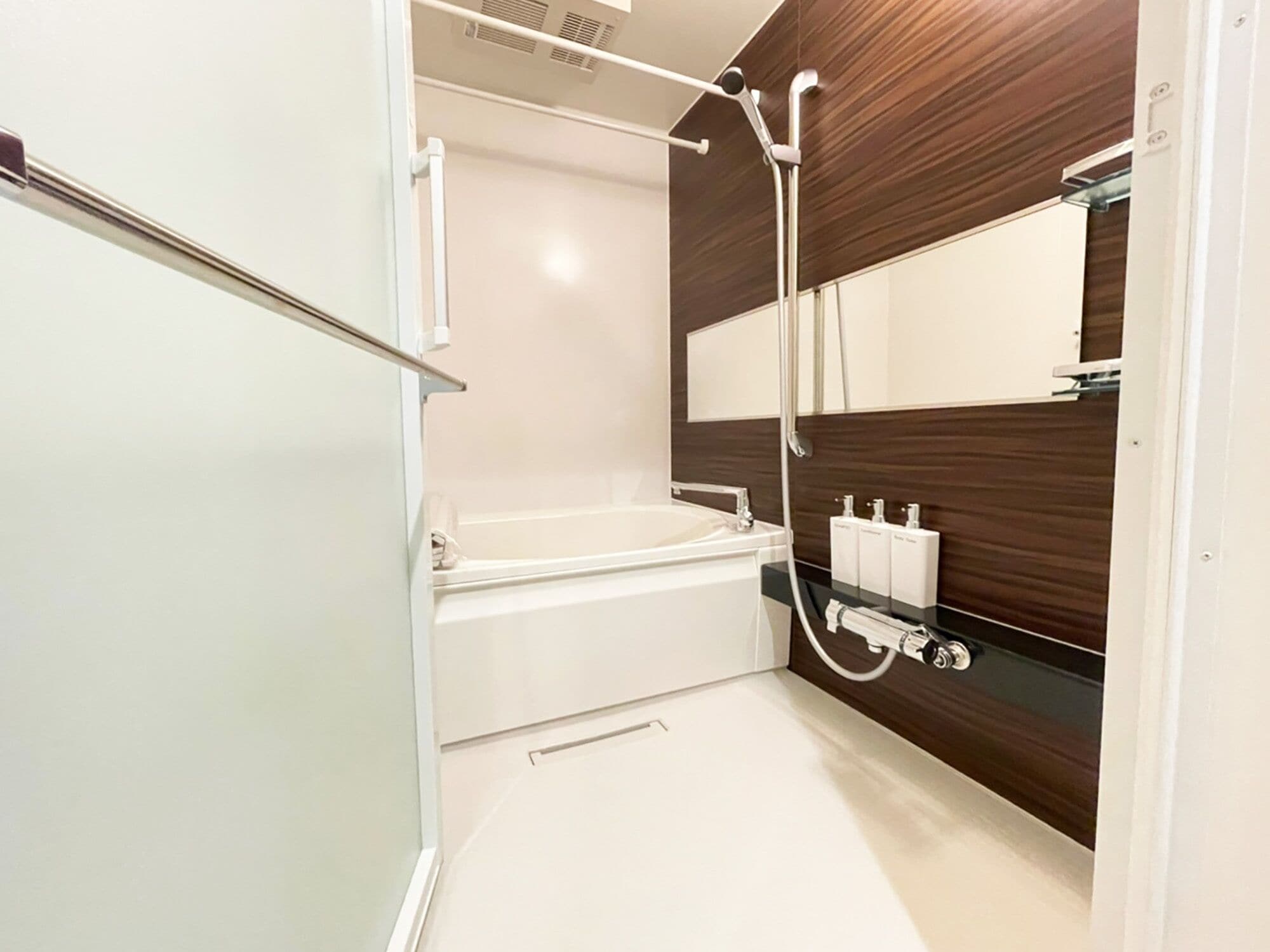 A modern bathroom with a bathtub, a shower, and a large mirror.