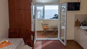 Una cocina con vistas al mar, una mesa de comedor con un cuenco de fruta y un televisor montado en la pared.