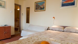 Habitación de hotel con cama, escritorio y baño visible a través de una puerta abierta.