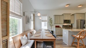 A modern kitchen with a central island, built-in appliances, and a seating area with a bench and chairs.