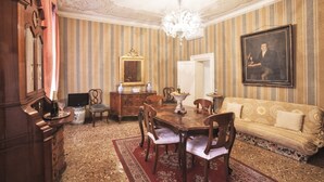 A formal dining room with a wooden table, chairs, a chandelier, and a sofa. - Deluxe Venetian Apartment at Rialto (Venezia)