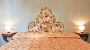A bed with an ornate headboard, two bedside lamps, and a patterned bedspread. - Deluxe Venetian Apartment at Rialto (Venezia)
