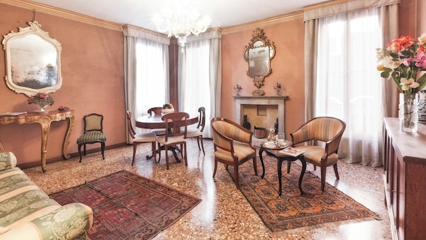 A spacious living room with a fireplace, a chandelier, and a dining area with wooden furniture. - Deluxe Venetian Apartment at Rialto (Venezia)