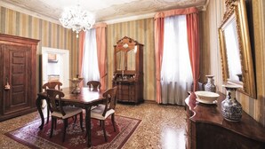A dining room with a wooden table, chairs, a chandelier, and a mirror. - Deluxe Venetian Apartment at Rialto (Venezia)
