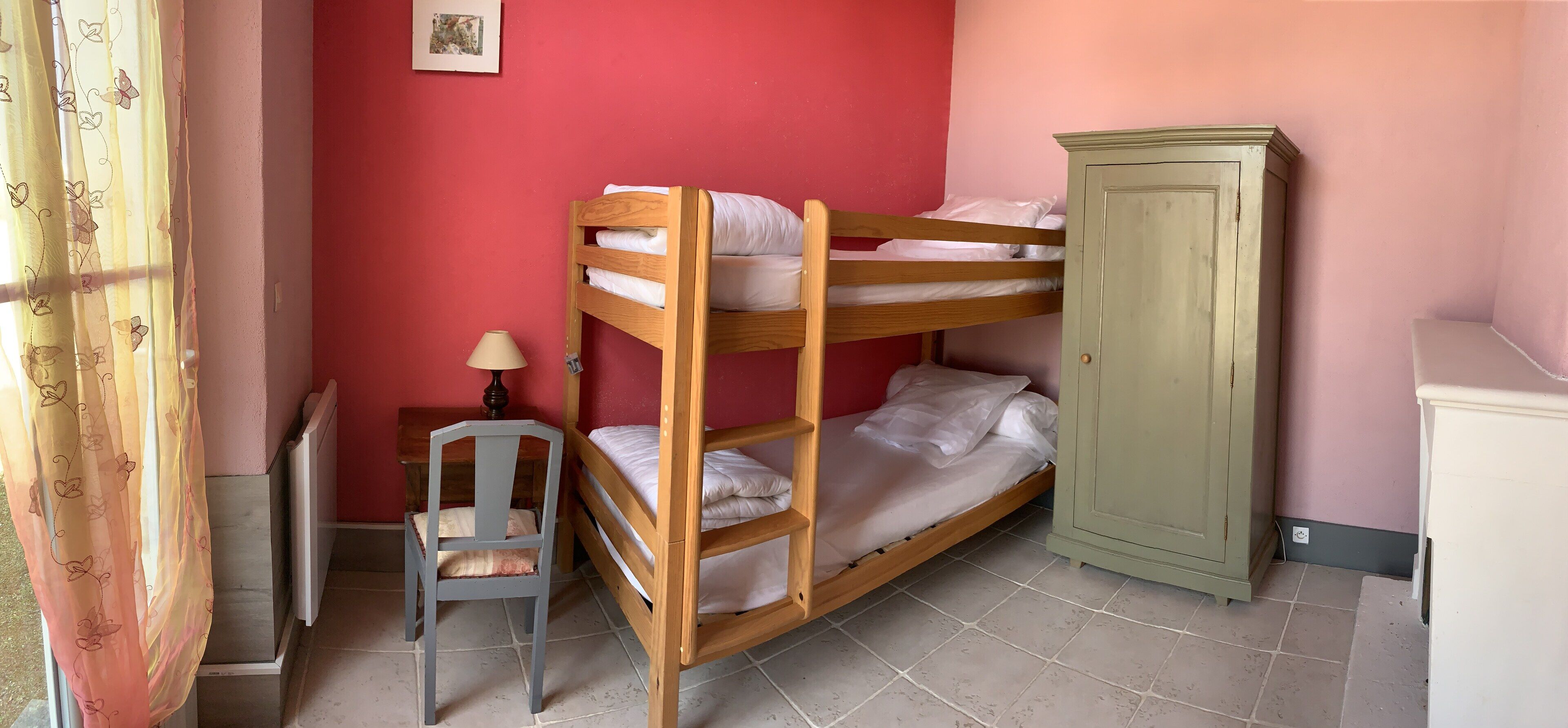 A bunk bed with a chair and a cabinet in a room with red walls.