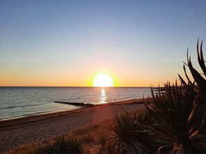 A beach at sunset with a clear sky, calm sea, and some vegetation in the foreground. - Spacious house in the Oleron region, in a quiet location, (Saint-Pierre-d'Oléron)