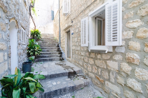 Una estrecha escalera de piedra que conduce a un edificio con contraventanas blancas.