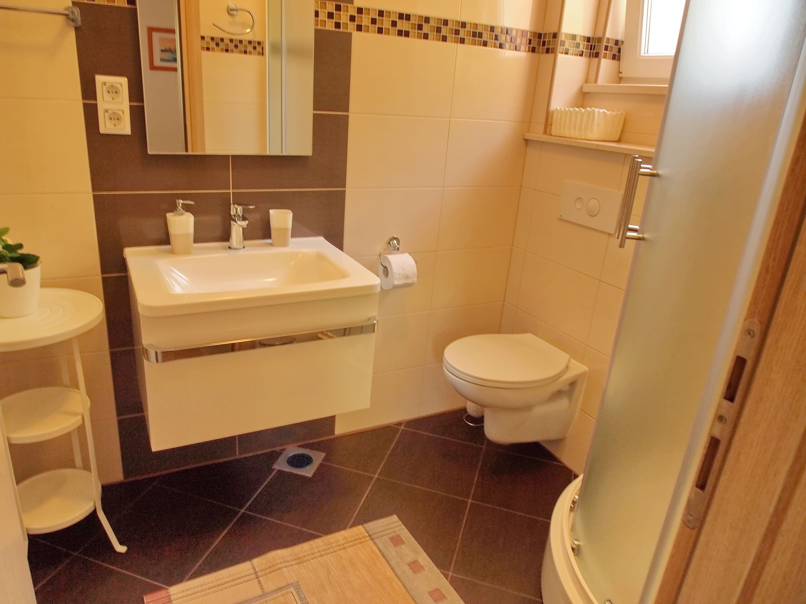 A bathroom with a sink, mirror, toilet, and shower.