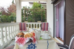 Ein Balkon mit einem Frühstückstisch, gedeckt mit Brot, Gebäck und einem Teekessel.