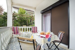 Ein Balkon mit Tisch und zwei Stühlen, bestuhlt, mit Blick auf Grünflächen.