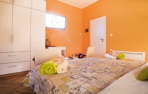 Ein Schlafzimmer mit einem Bett, einem Schreibtisch, einem Stuhl und einem Kleiderschrank.