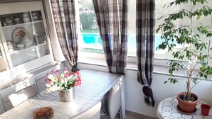 Ein Essbereich mit Tisch, einer Topfpflanze und einem Fenster mit Vorhängen.