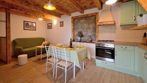 Eine gemütliche Küche mit Esstisch für zwei Personen, einem grünen Sofa und einer Wandverkleidung aus Naturstein.