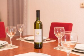 A dining table with a bottle of Chardonnay wine, glasses, and plates set for a meal. - Apartments Grga (Dubrovnik)