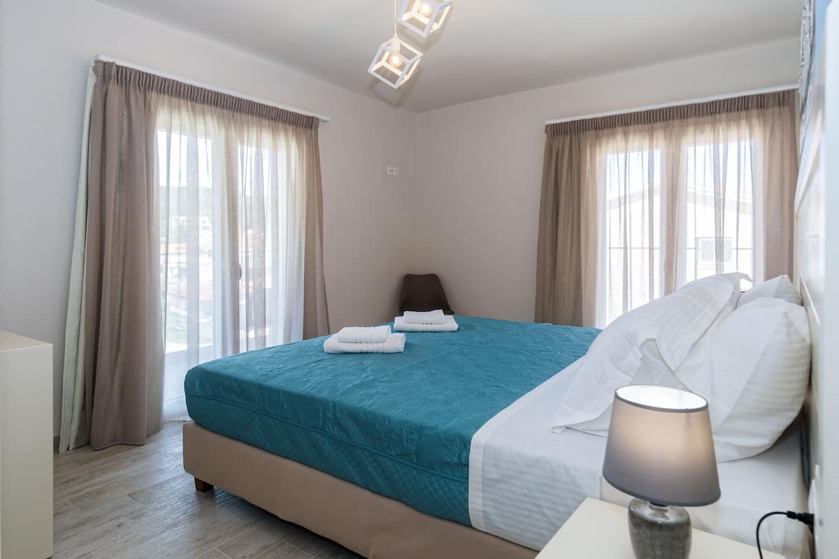 Una habitación de hotel con una cama, una mesita de noche, una lámpara y cortinas.