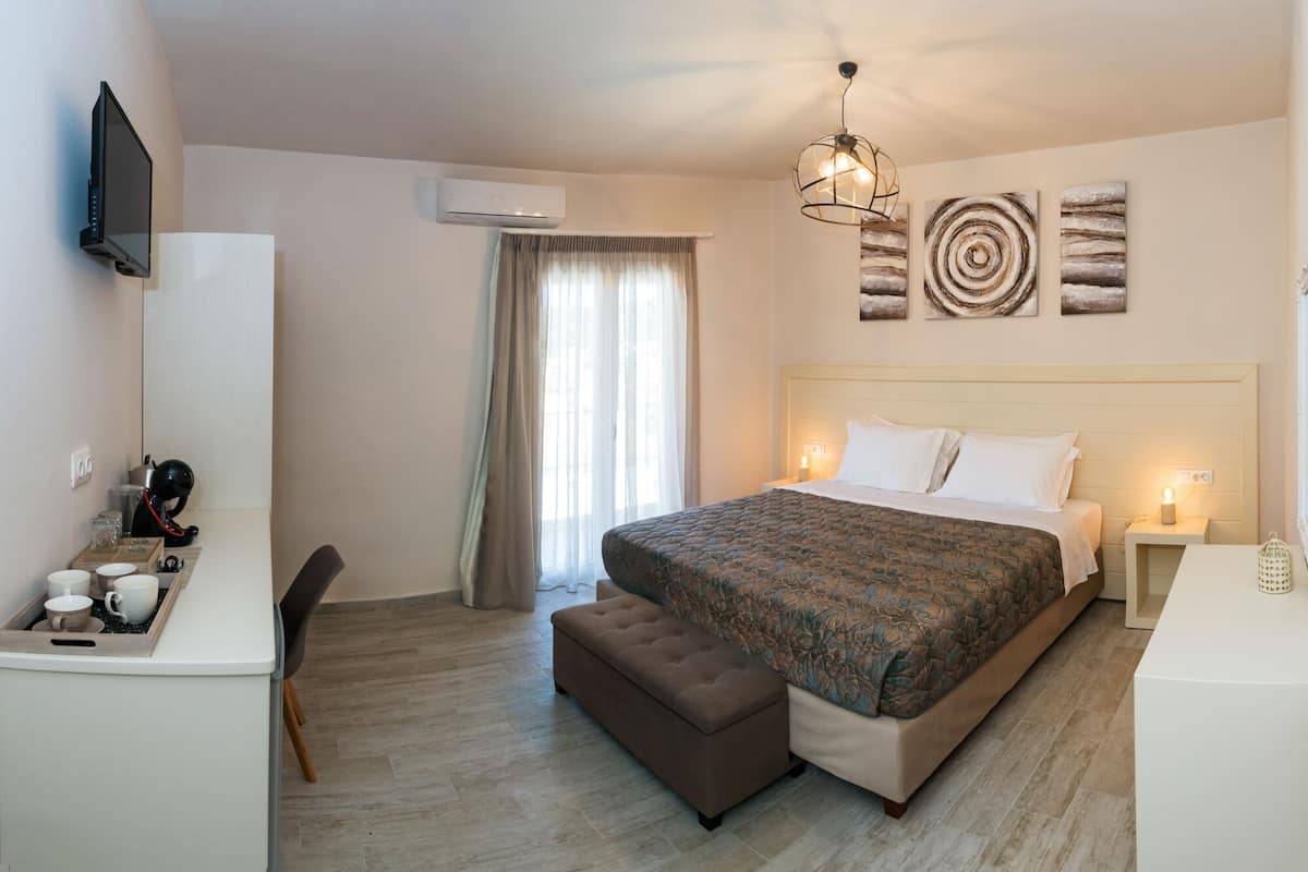Habitación de hotel con cama, mesitas de noche, escritorio con silla, televisión y cuadros en la pared.