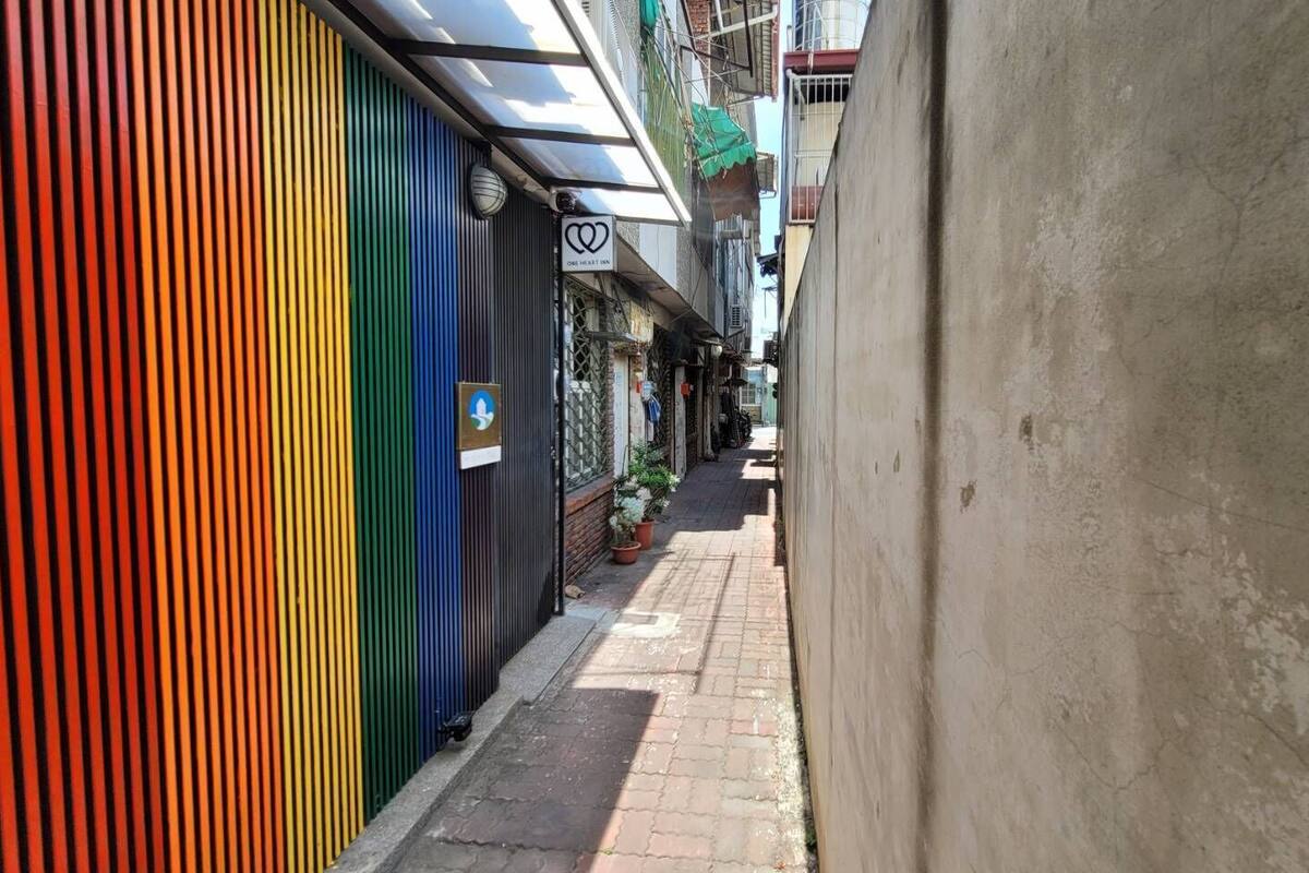 A narrow alley with colorful buildings, a One Heart Inn sign, and a potted plant.