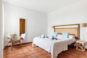 A hotel room with a bed, a chair, a bedside table, and a lamp. - Villa Poppy. Private pool, Full AC & Wifi, Menorca (Sant Lluís)