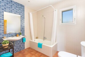Une salle de bain avec une baignoire, un lavabo, un miroir et une fenêtre.