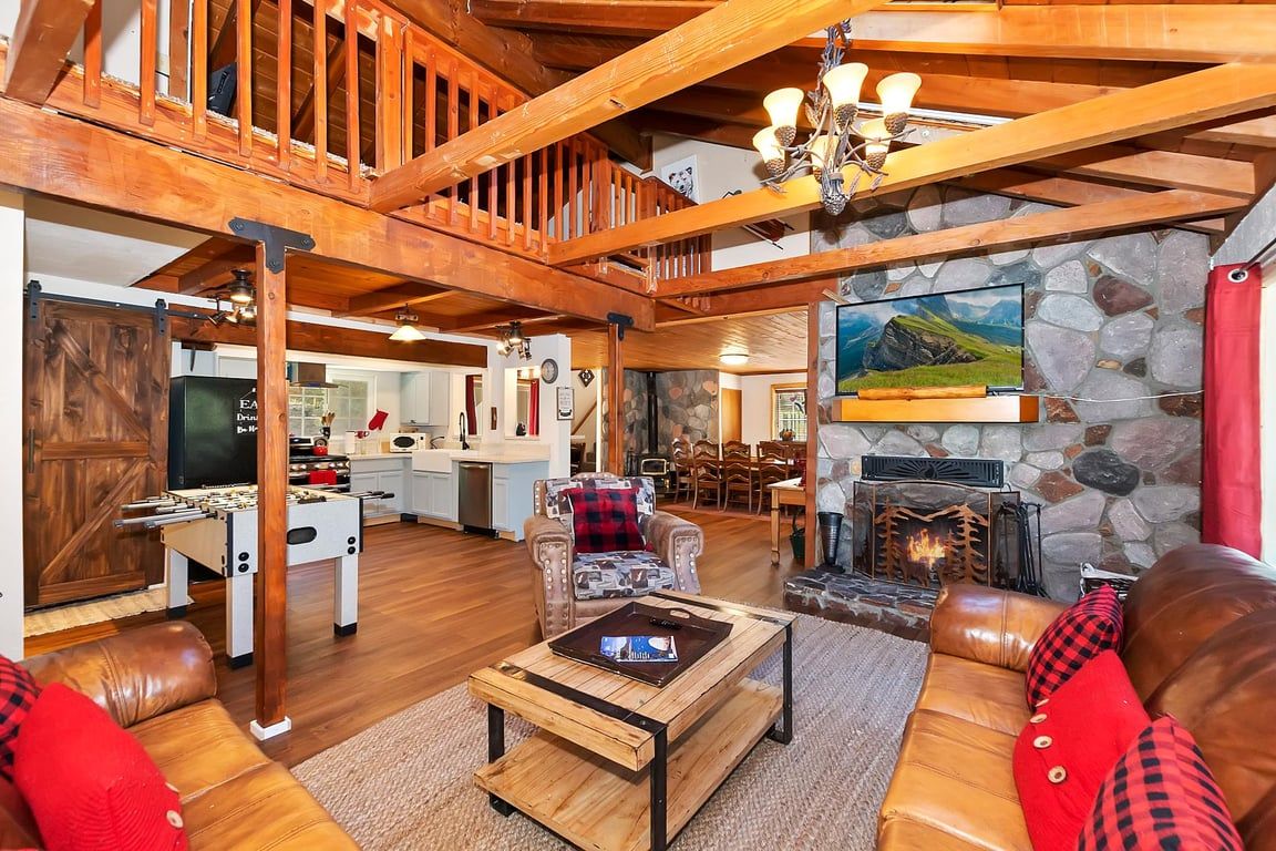 A spacious living area with a high ceiling, wooden beams, a fireplace, and a cozy seating arrangement.
