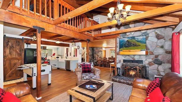 A spacious living area with a fireplace, wooden furniture, and a kitchen in the background.