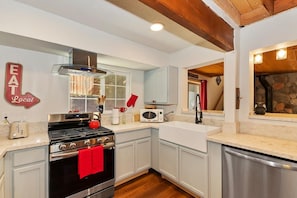 A kitchen with a stove, microwave, and a red towel hanging on the oven. - Close to Bear Mountain & Golf Course! Hot Tub! Fenced Yard! Foosball! (Big Bear Lake)