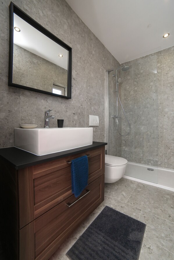 A modern bathroom with a large mirror, a sink, a toilet, and a shower. - Apartments Martic (Supetar)