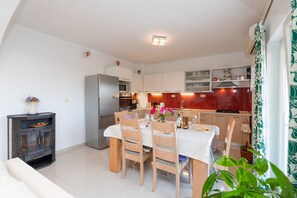 A modern kitchen with white cabinets, a stainless steel refrigerator, and a dining area with a table and chairs.