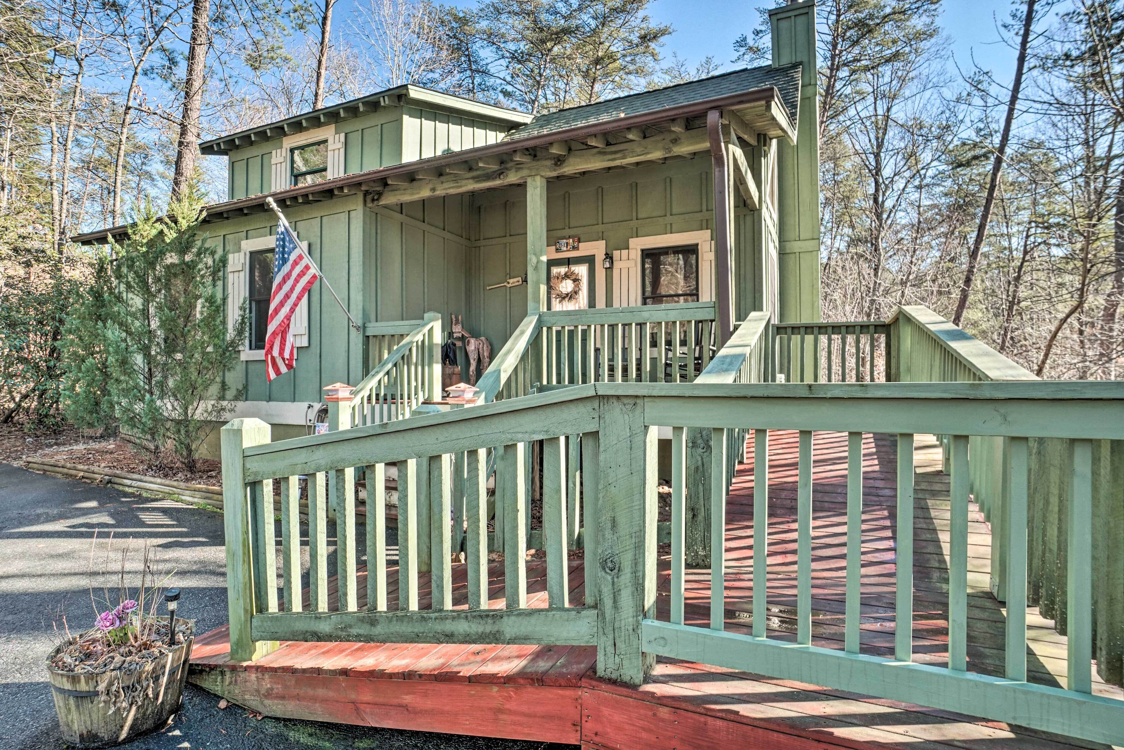 A green wooden cabin with a porch and a red deck.