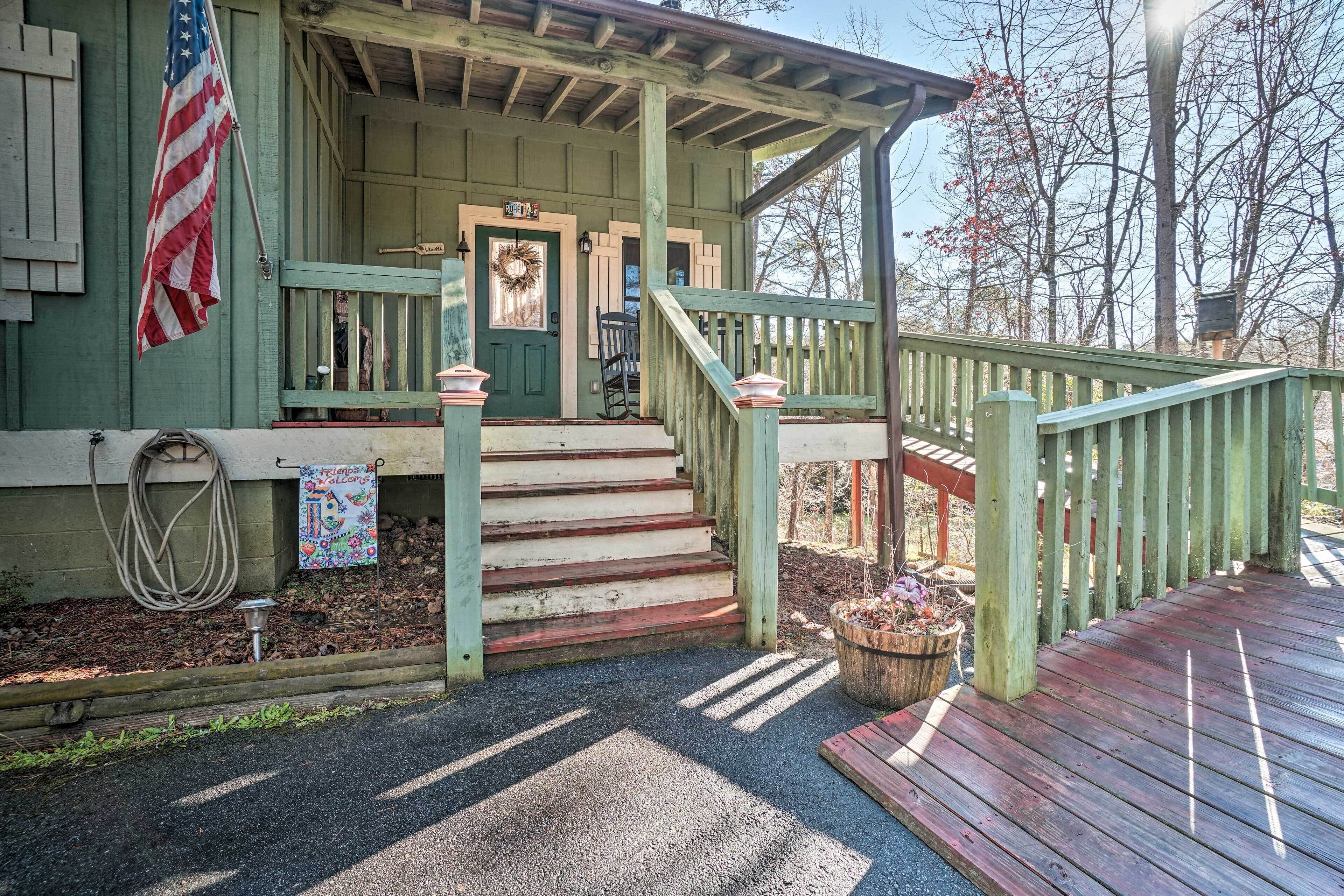 A wooden porch with a green door, a wreath, and a flag.