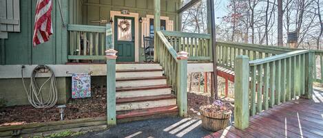 A wooden porch with a green door, a wreath, and a flag.