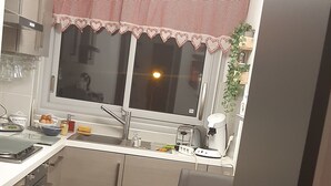 A compact kitchen with a window, a sink, and a small dining area with a table and chair.
